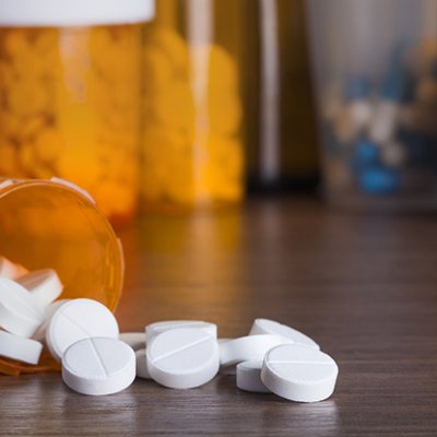 White tables spilled onto a table in front of a medicine container